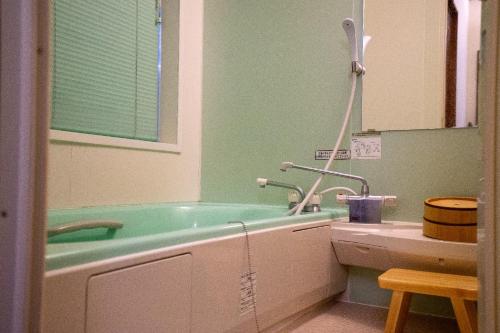 a bathroom with a green tub and a sink at Jomon no Yado Manten in Yakushima