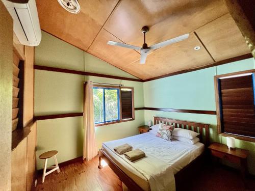a bedroom with a bed with a ceiling fan at Tropical Cabin Retreat in Mission Beach