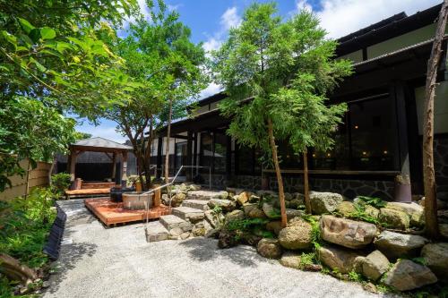 a house with a stone wall and trees in front of it at Jomon no Yado Manten in Yakushima