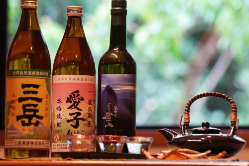three bottles of wine on a table with a teapot at Jomon no Yado Manten in Yakushima