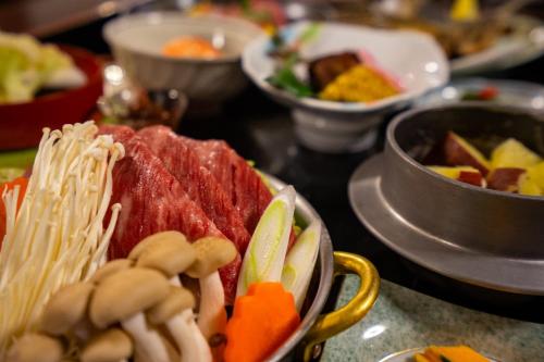 a bowl of food with meat and vegetables on a table at Jomon no Yado Manten in Yakushima