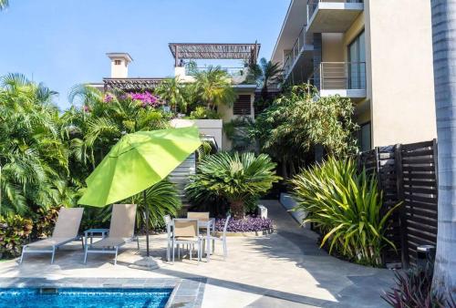 eine Terrasse mit Stühlen und einem Sonnenschirm neben einem Pool in der Unterkunft Gorgeous Open Concept Apartment in Santa Cruz Huatulco