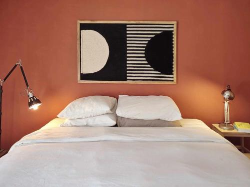 a bedroom with a white bed with a painting on the wall at Queen Bedroom in Aljezur