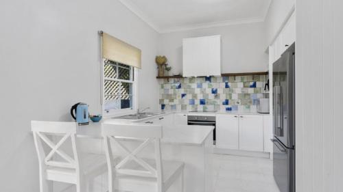 una cocina blanca con armarios blancos y electrodomésticos blancos en Classic Holiday House, en Woorim