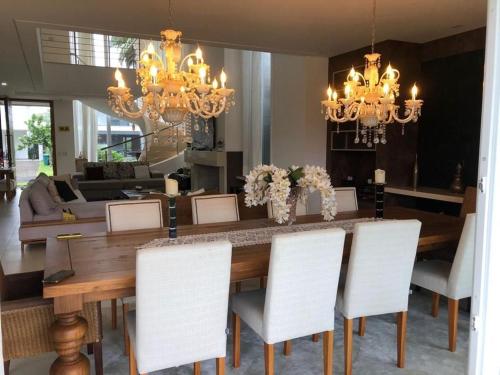 a dining room with a wooden table and white chairs at Casa Luxuosa no Condomínio Villaggio Atlântida in Xangri-lá