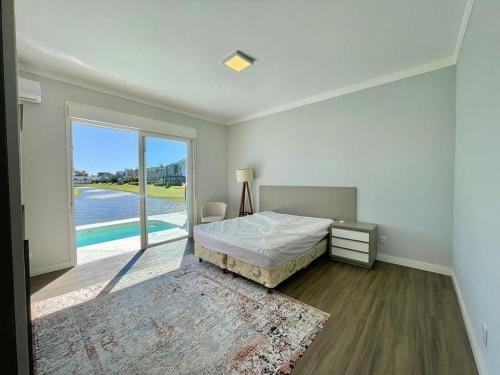 ein Schlafzimmer mit einem Bett und Blick auf einen Pool in der Unterkunft Casa Luxuosa no Condomínio Ilhas Resort in Capão da Canoa