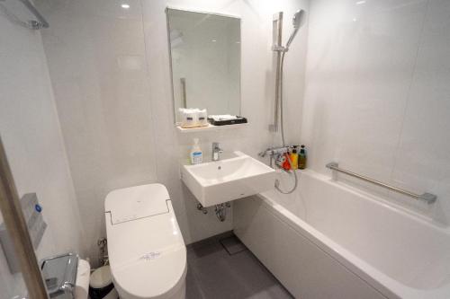 a white bathroom with a toilet and a sink at Marine Blue Yakushima in Yakushima