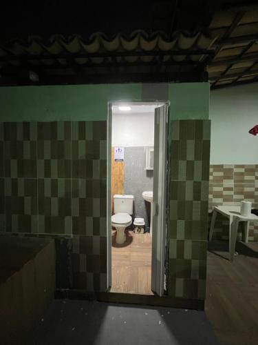 a bathroom with a toilet in a room with tiles at Dr House veraneio Abaís praia SERGIPE in Praia Da Caueira
