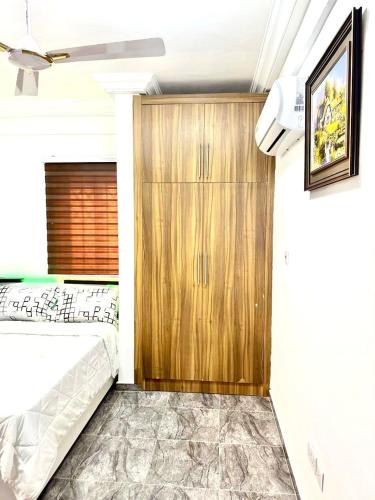 a bedroom with a bed and a wooden cabinet at Kan's Krib in Accra