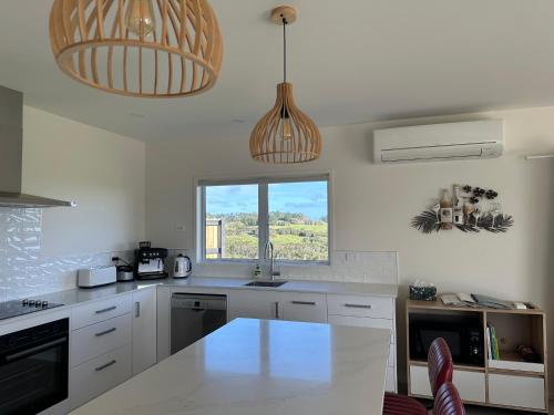 a kitchen with white counters and a window and pendant lights at Far North Panorama in Kaingaroa