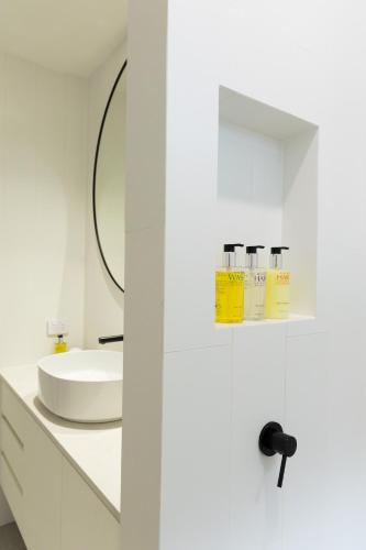 a white bathroom with a sink and a mirror at Surfside Retreat in Gnarabup