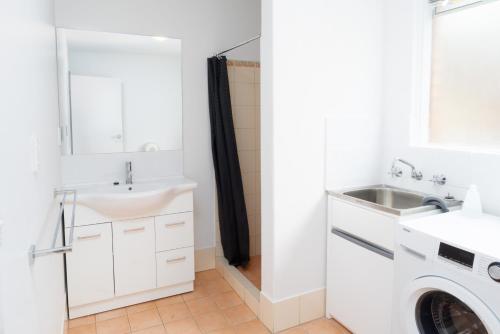 a bathroom with a sink and a washing machine at Apartment 16 Burswood in Perth