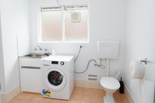 a bathroom with a washing machine and a toilet at Apartment 16 Burswood in Perth