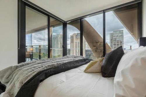a bed in a room with large windows at Lavish Condo Prestigious St Kilda Rd Boulevard in Melbourne