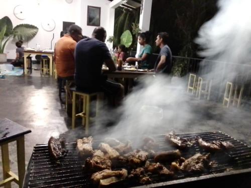 a group of people cooking meat on a grill at Sara's Grove Boutique Bungalow in Haputale