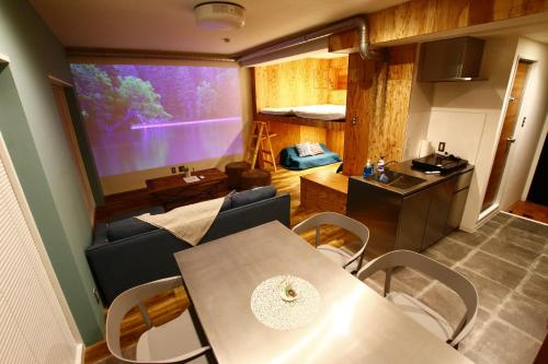 a living room with a table and a large screen at 365BASE outdoor hostel in Hamamatsu