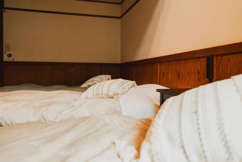 a large bed with white sheets and pillows at Hakuba Pension & Log Hotel Meteor in Hakuba