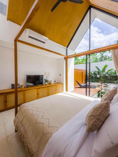 a bedroom with a large bed with a large window at Tannari Villa Ubud in Ubud