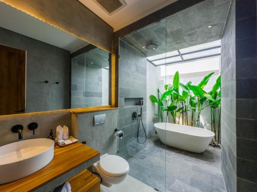 a bathroom with a white tub and a sink at Tannari Villa Ubud in Ubud
