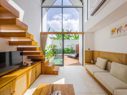 a living room with a large window and a staircase at Tannari Villa Ubud in Ubud