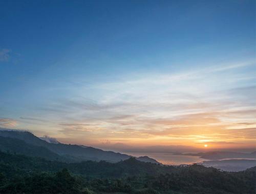 a sunset over a mountain range with the sun in the sky at Narra Hill Tagaytay in Laurel