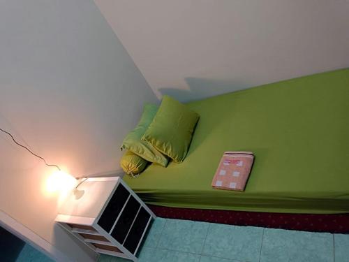 a room with a green bed with a lamp at OIKOS GREEN - Homestay in Kuningan