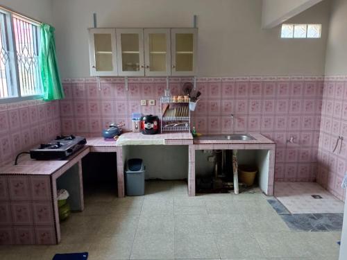 a kitchen with pink tiled walls and a table at OIKOS GREEN - Homestay in Kuningan
