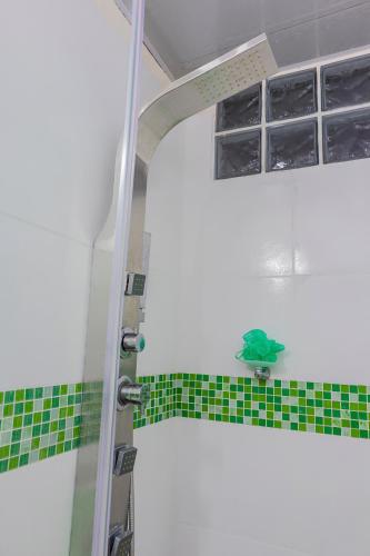 a bathroom with green and white tiles and a shower at Casa Encanto Buga in Buga