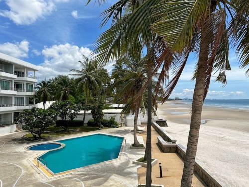 a swimming pool next to a beach with palm trees at Seaview 2 bed in the heart of Hua Hin - BP2 in Hua Hin