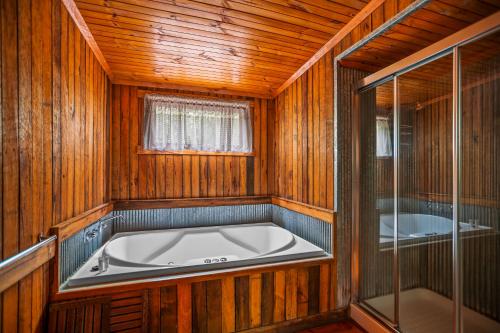 una grande vasca da bagno in una stanza di legno con una finestra di StayAU Cedar Lodge 3BR Quaint Countryside Cottage a Badger Creek