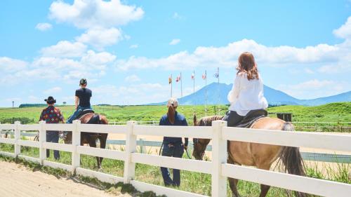 a group of people riding horses near a fence at El Patio Ranch in Aso
