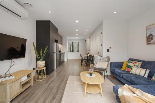 Una sala de estar con un sofá azul y una mesa. en Spring Special CBD Free Parking, en Christchurch