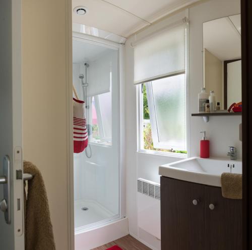 a bathroom with a shower and a sink and a mirror at Camping Officiel Siblu Les Pierres Couchees in Saint-Brevin-les-Pins