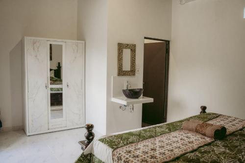 een slaapkamer met een bed, een wastafel en een spiegel bij Kubu Silvia in Nusa Dua