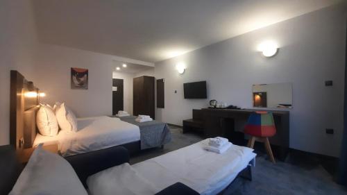 a hotel room with two beds and a desk at Хотел Релакс in Kazanlŭk