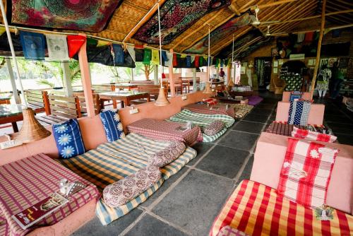 a row of couches and tables in a restaurant at Hampi Waterfall Cottages in Hampi