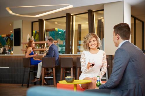 a man and a woman sitting at a table with a glass of wine at Holiday Inn Express Adelaide City Centre by IHG in Adelaide