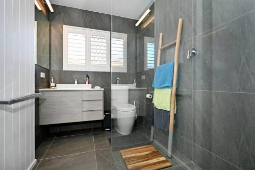 a bathroom with a toilet and a sink and a shower at Waterfront Stylish Luxury, Light, Relaxed in Parrearra