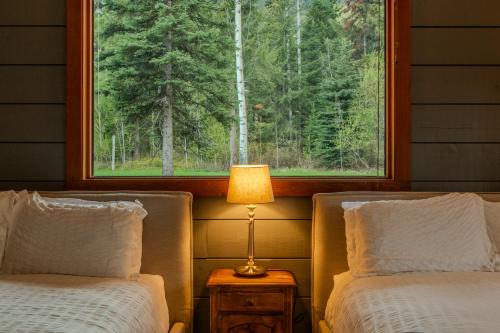 two beds in a room with a window and a lamp at Winston Lodge in Golden