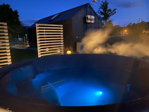 a blue hot tub in front of a building at Holiday Hill Karpnki, Sauna, Domek Hygge-balia, Domek Lagom-jacuzzi in Karpniki