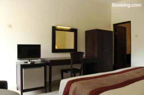 a bedroom with a desk with a computer and a mirror at Sarinande Hotel in Seminyak