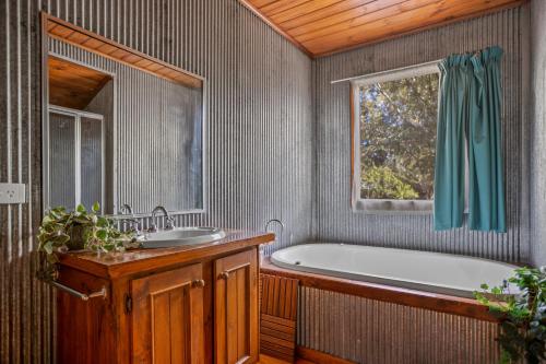 un bagno con vasca, lavandino e finestra di StayAU Birchwood Cottage 2BR Yarra Valley Cottage a Badger Creek
