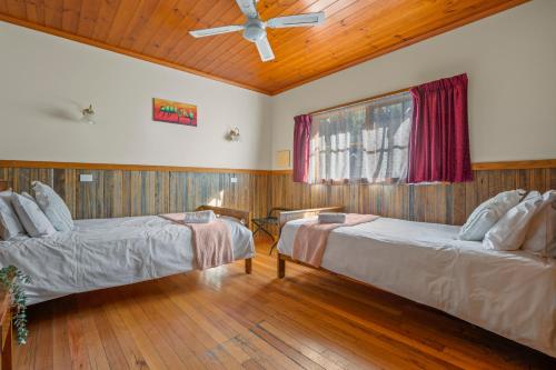 2 Betten in einem Zimmer mit Deckenventilator in der Unterkunft StayAU Conifer Cottage 2BR Serene Lakeside Haven in Badger Creek