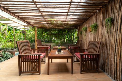 a patio with chairs and a table and a wooden ceiling at Bamboo Bay Eco Resort in Srithanu