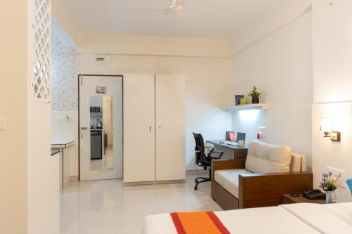 a room with a bed and a desk and a kitchen at Bauhinia in Pune