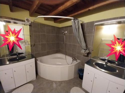 a bathroom with a tub and two sinks and a toilet at Escale de la Jurade in Rogues