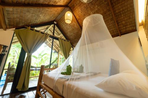 a bedroom with a bed with a mosquito net at Bamboo Bay Eco Resort in Srithanu