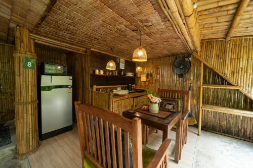 a kitchen with a refrigerator and a table and chairs at Bamboo Bay Eco Resort in Srithanu