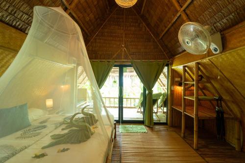 a bedroom with a canopy bed in a hut at Bamboo Bay Eco Resort in Srithanu