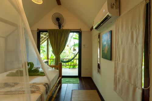 a bedroom with a bed with a mosquito net and a window at Bamboo Bay Eco Resort in Srithanu
